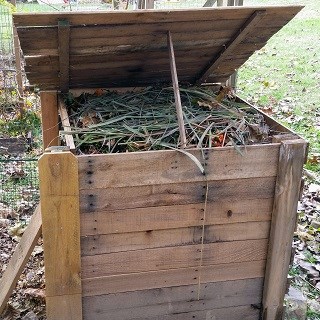 An open and full homemade wooden home composting bin