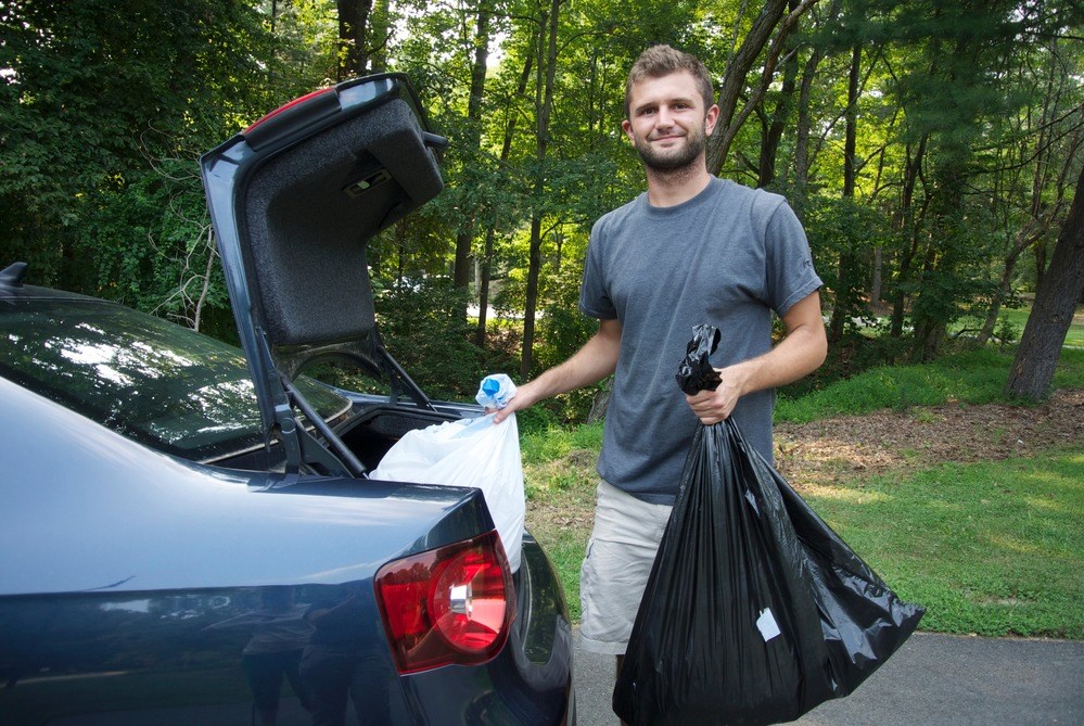 Man putting trash bags in vehicle trunk