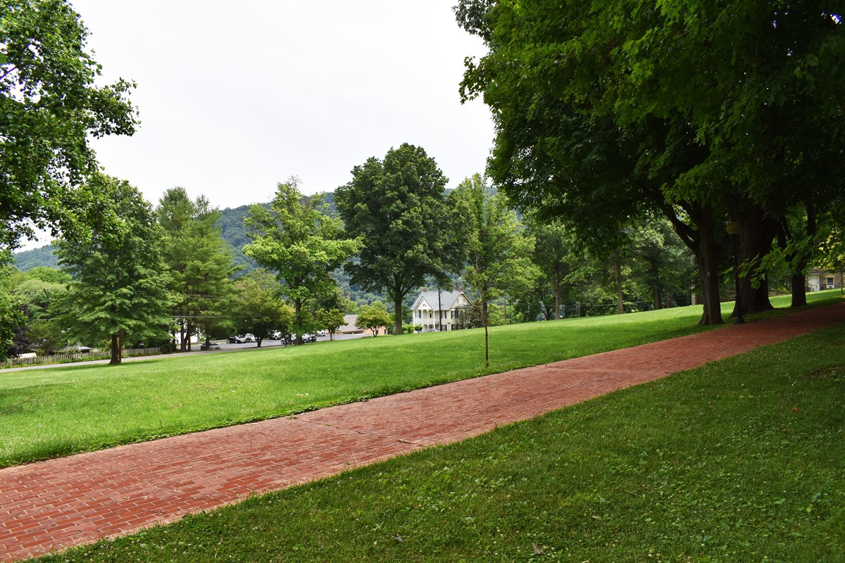 Brick path runs past large grassy area with mountains in the distance