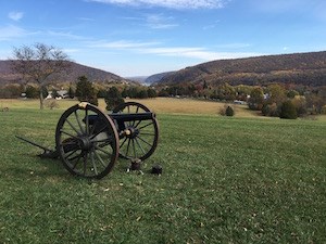 an artillery piece on the fall landscape; in the distance is a gap in the mountains