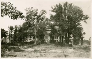 The Grange is hidden behind a cluster of trees. A dense cluster, to the right of the house, are the tallest in the photo.