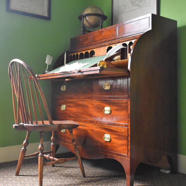 A brown desk with an 18-century chair.