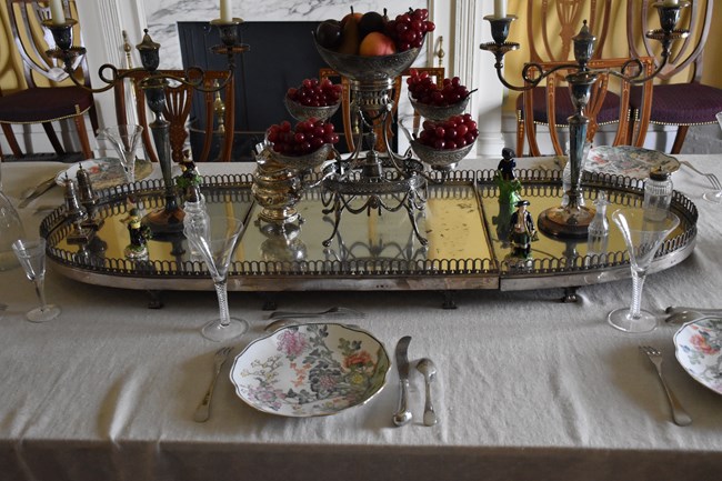 A table upon which is an oval and oblong mirrored platter, standing on small legs.