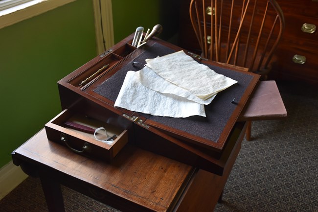 A wooden writing desk sitting upon a tea table.