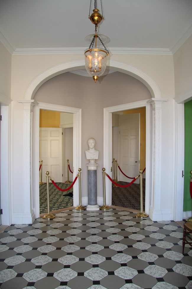 An entrance hall with an archway, inside which are two symmetrical doors.