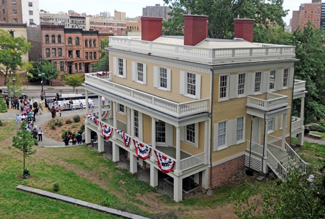 A yellow house surrounded by people.