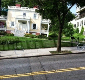 View of the Grange from the road, showing that the road is on a hill, and there are bike racks in front of the building.