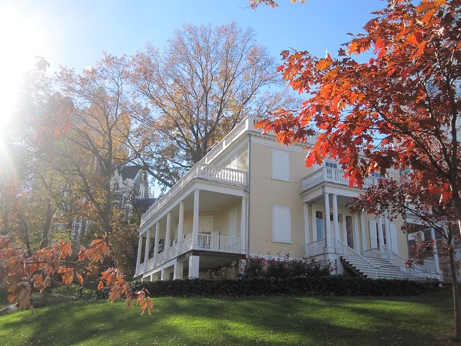 A yellow house is surrounded by fall foliage.