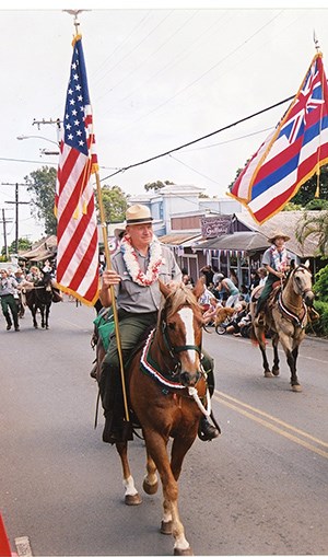 Reeser holding flag at Makawao Parade.