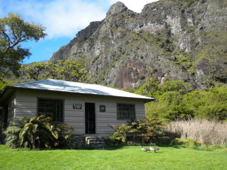 cabin in a field area with cliffs in the background