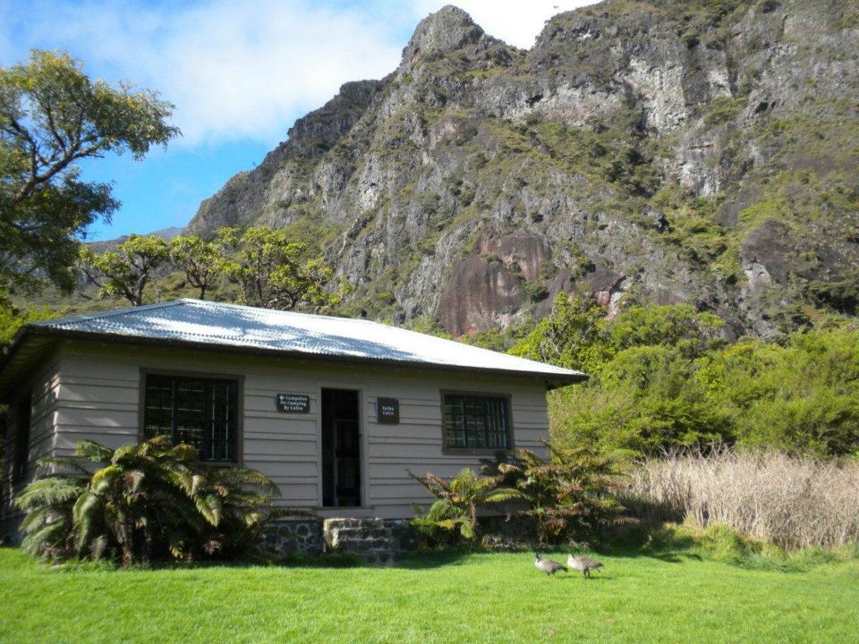 Crater_Paliku_NPS photo cabin in a field area with cliffs in the background
