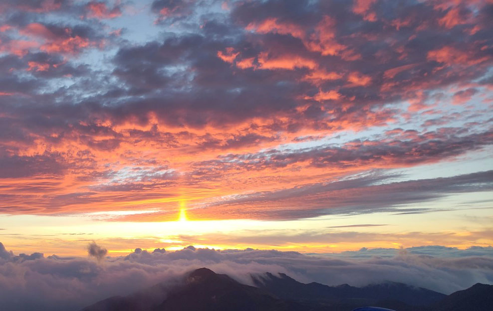 NPS Photo Haleakala Sunrise by Gabe Ahrens Sun rising between colorful clouds and Haleakala Crater jagged peaks in background
