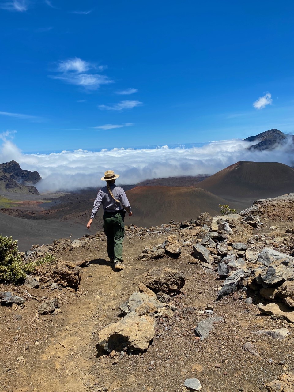 woman hiking on trail with large volcanic crater views