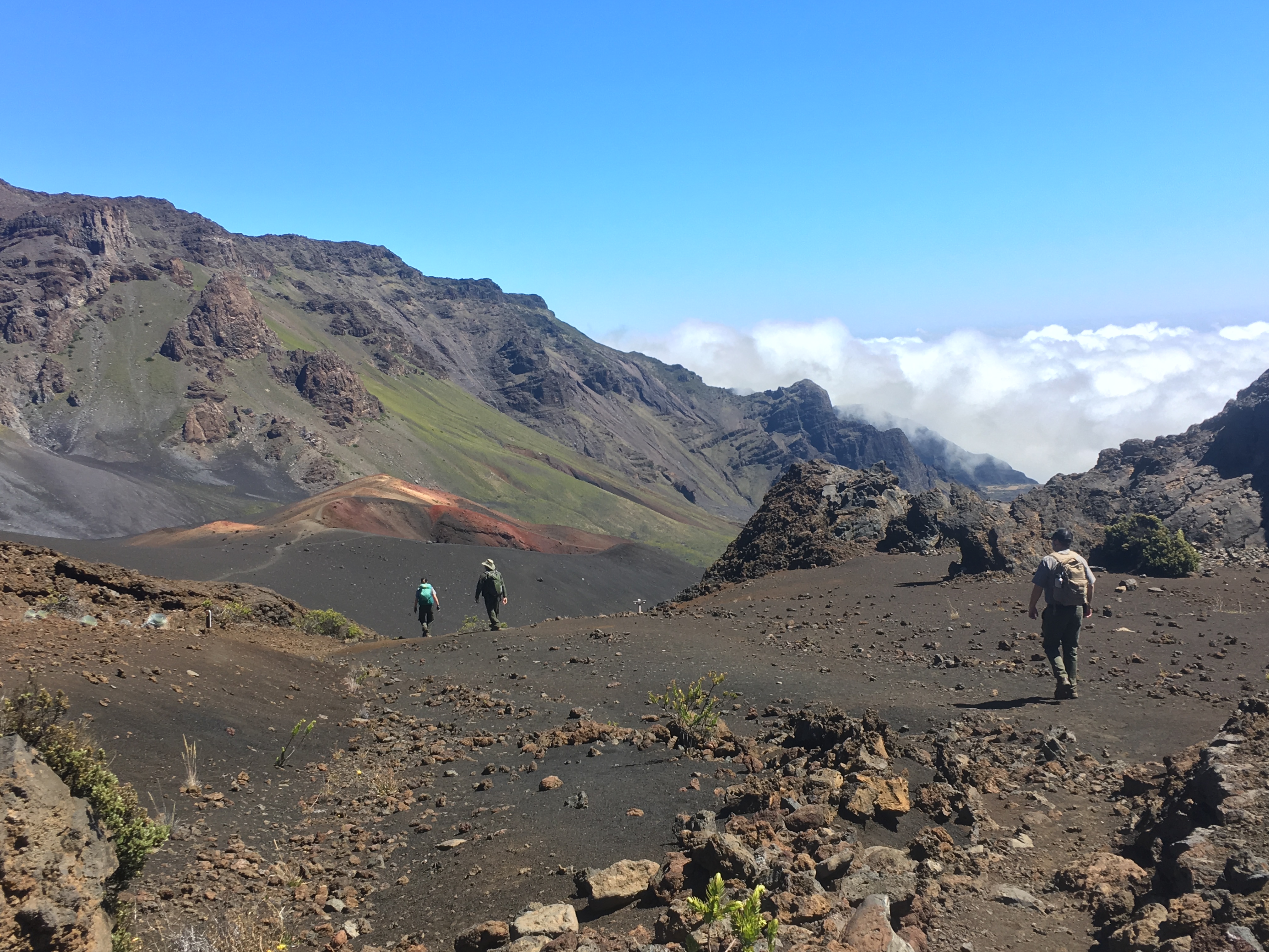 3 people walking in a volcanic crater with sweeping landscape views