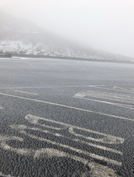 NPS Photo. Wintery mix and ice accumulating in parking lot at Haleakalā Visitor Center at 9,048 feet on February 3, 2021 slush covered asphault parking lot and snowy scenery