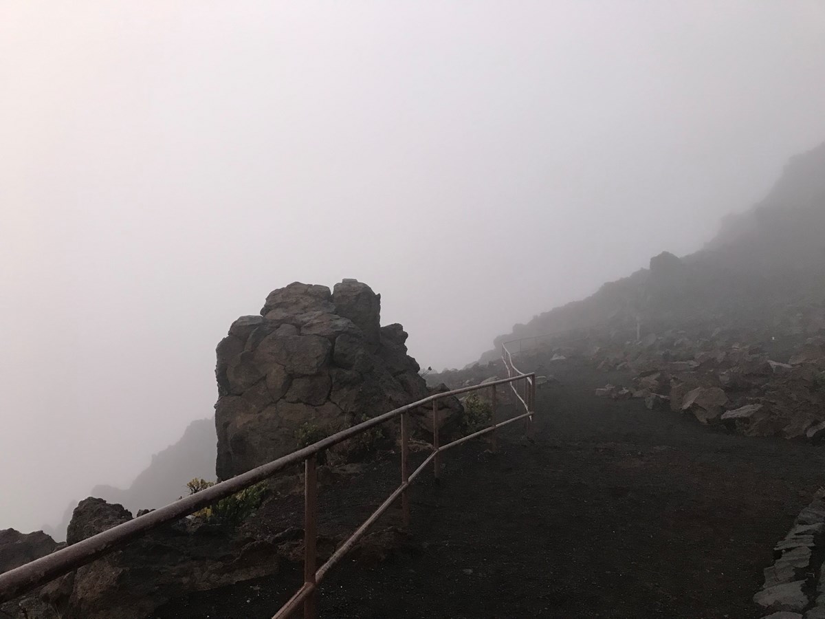 The overlook area and railing at Haleakala Visitor Center socked in with clouds.