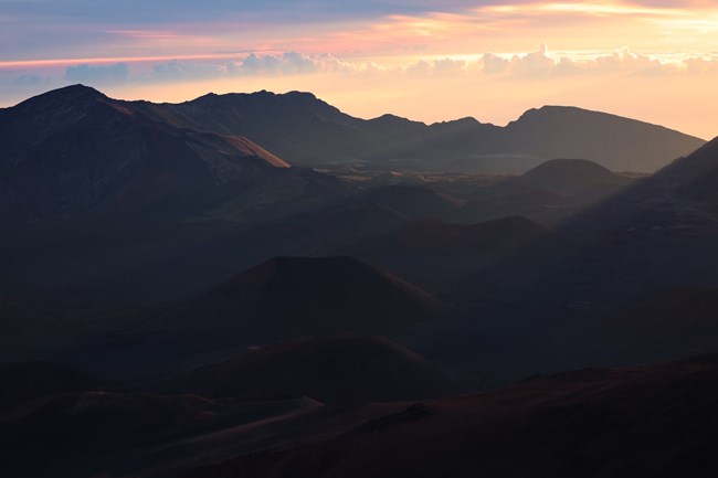 Dark, shadowy mountain with sunrise background