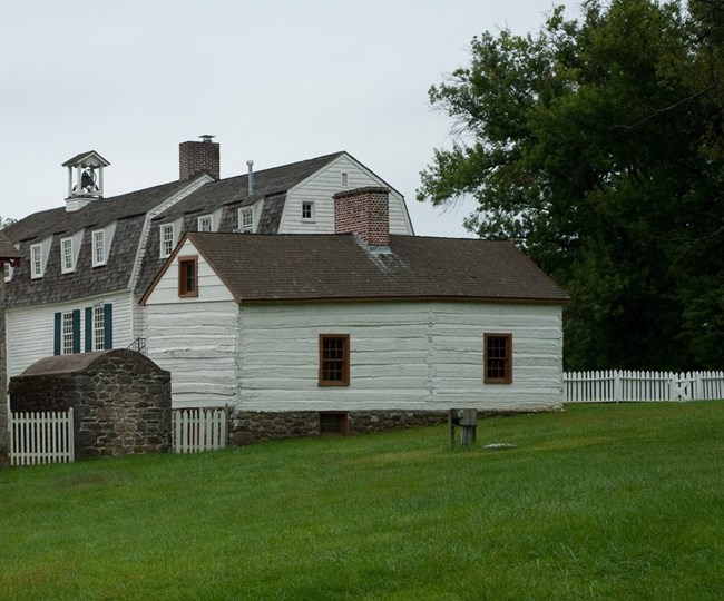 A modern day photograph of the rear of the log house and ash house.