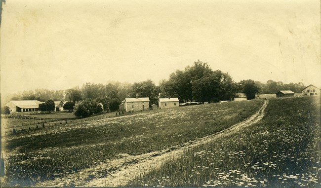 A historic black and white photograph of farm side buildings.