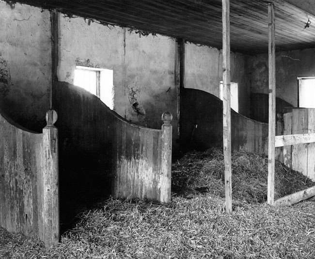 A historic black and white photograph of the interior of the stables.