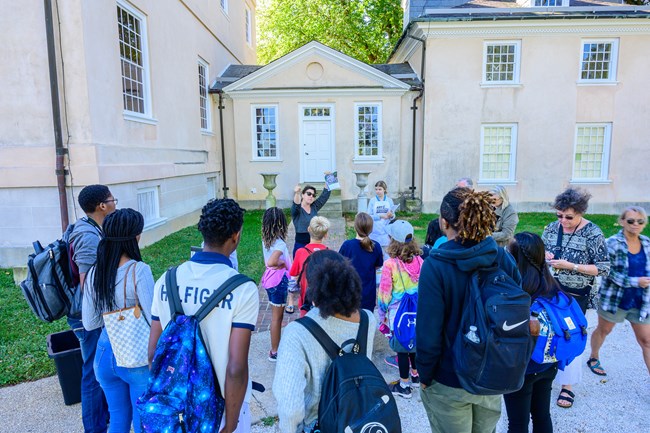 A teacher leads students in front of the Hampton mansion.