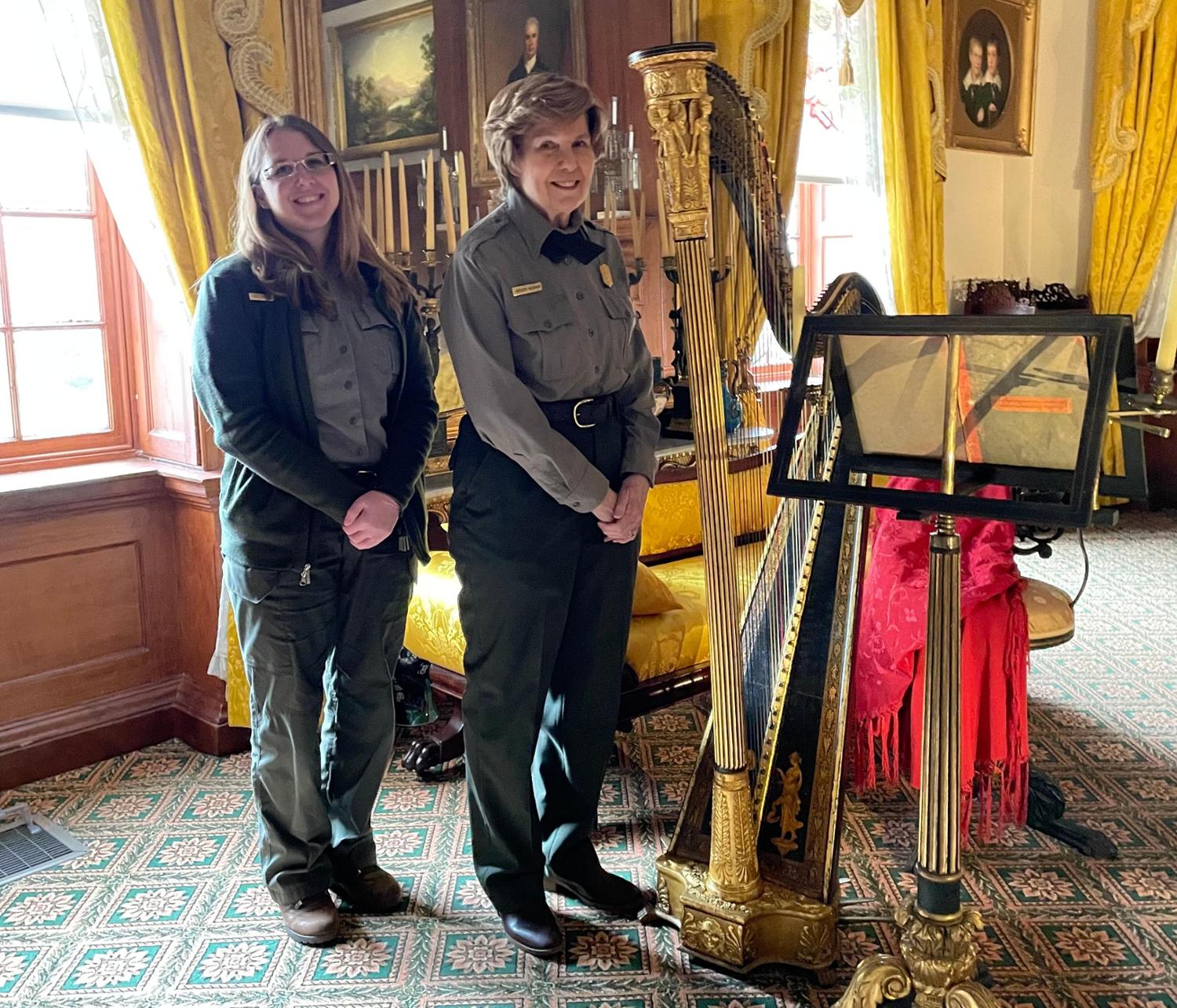 Curatorial staff with restored Erard harp Curators standing beside restored harp in music room