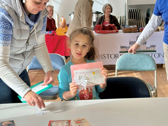 Young visitor holding up holiday craft