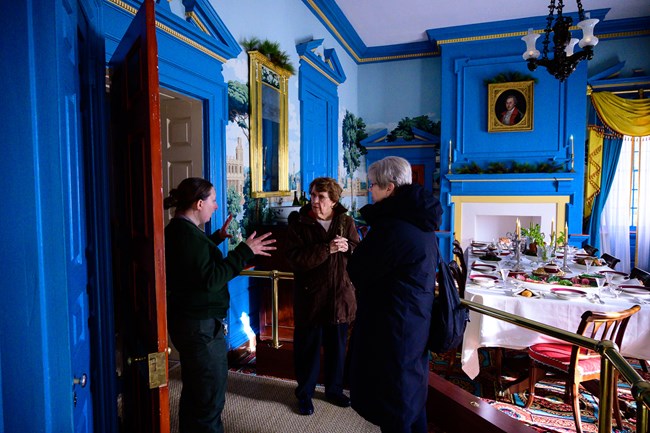 A ranger giving a tour to two visitors in the Hampton mansion.