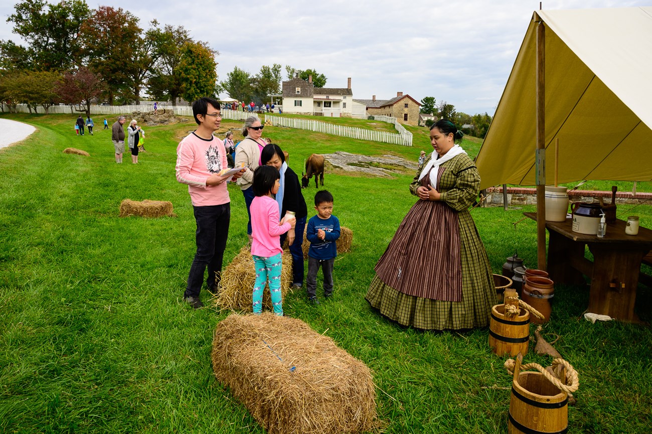 A family talks with a living historian during Harvest Day.