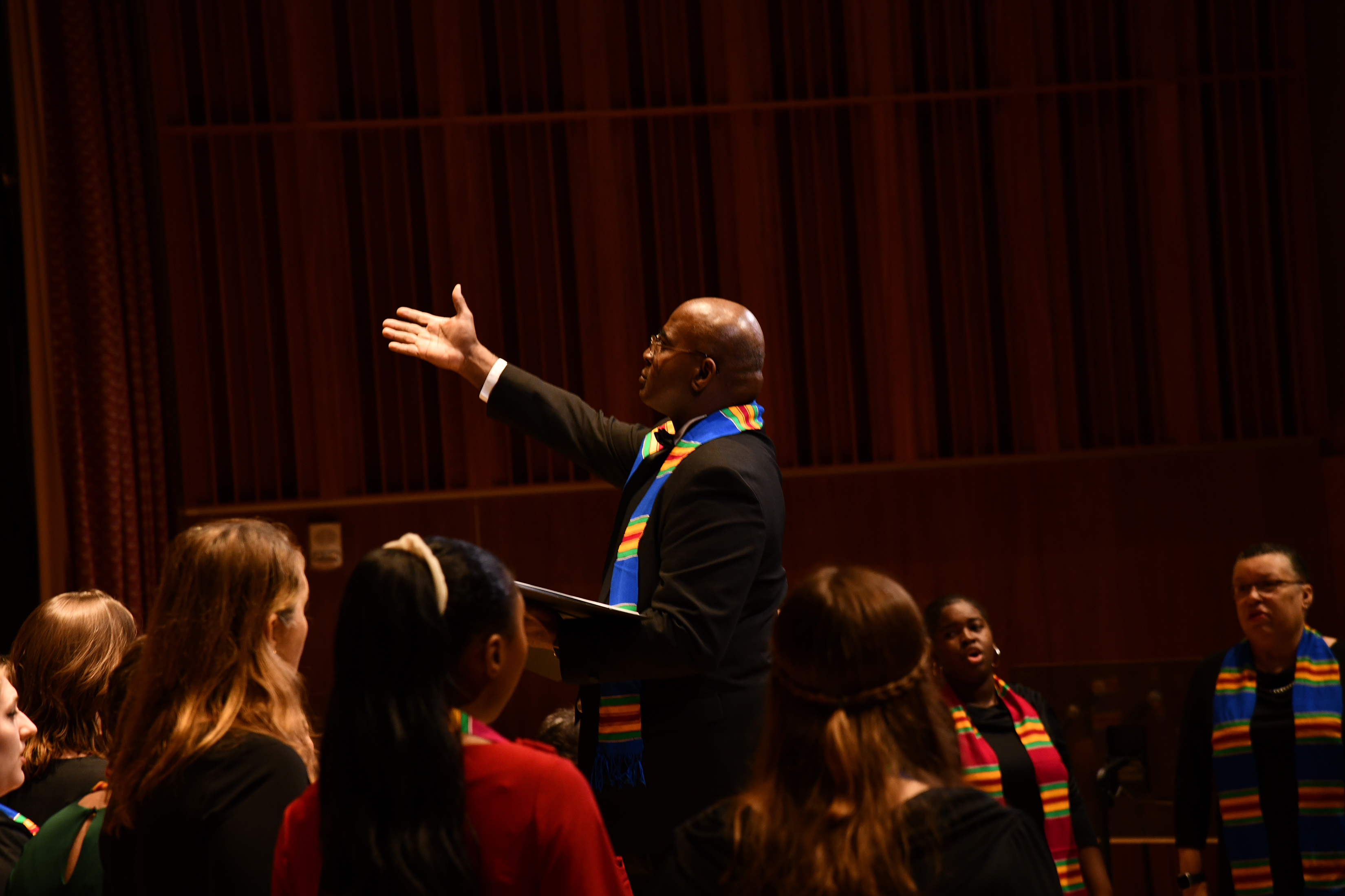 The Dorothy Coton Jubilee Singers A director raises his hand and stands among a group of singers