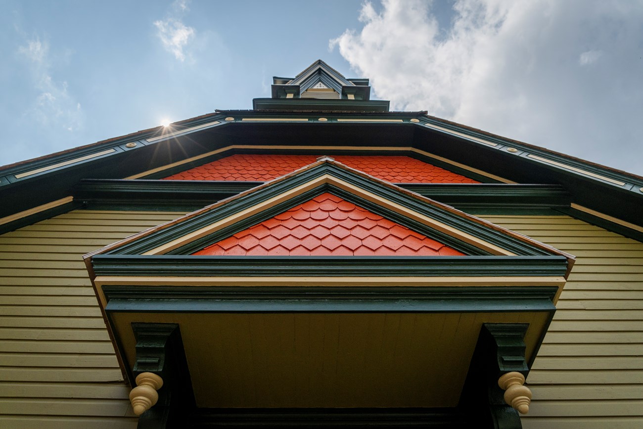 A low angle looking up the front of a green and orange colored church building.