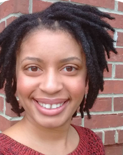 April Caddell standing in front of brick wall.