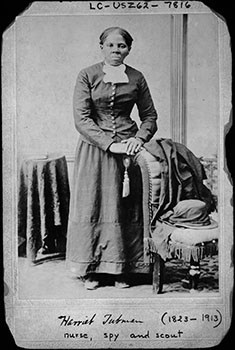 Image of African American woman standing with hands on chair back