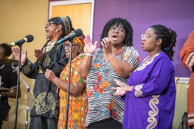 Performers in West African attire singing spirituals.