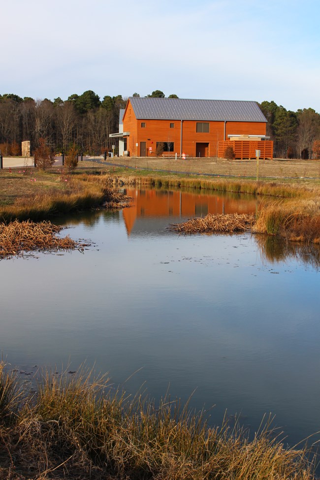 South side of the visitor center reflected in a blue pond