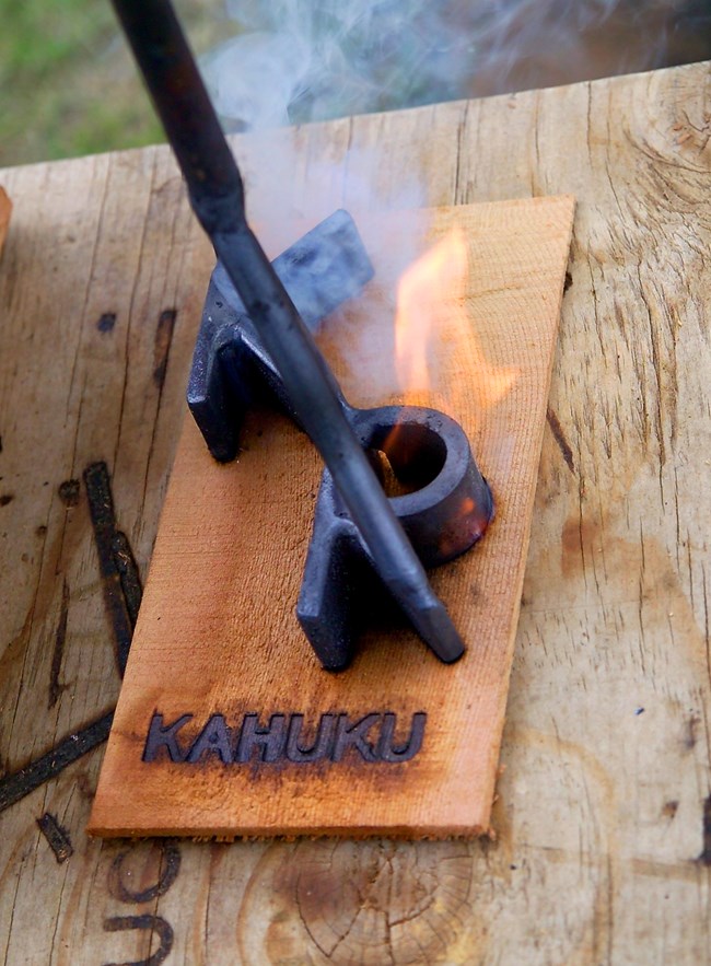 Branding iron for the Kahuku Ranch burning onto a piece of wood