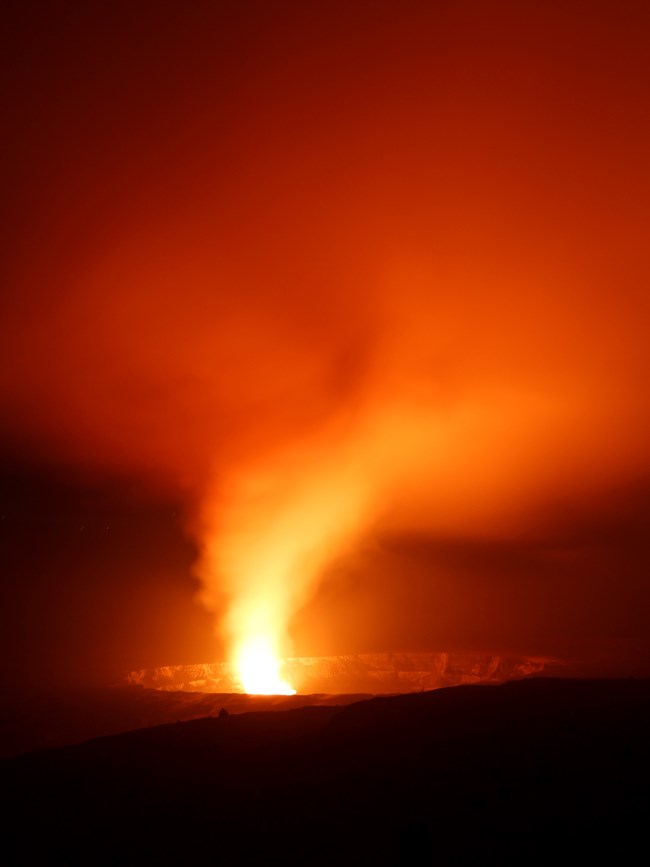 Glowing lava lake in a volcanic crater at night