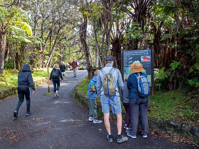 Visitors walking at a trailhead and observing a sign.