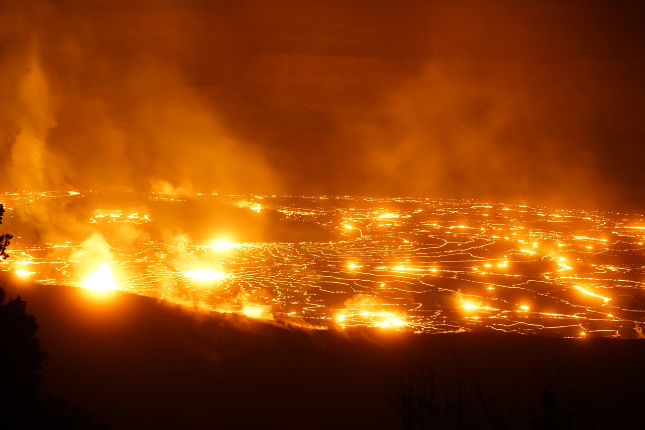 A large lava lake producing several fountains of lava at night.