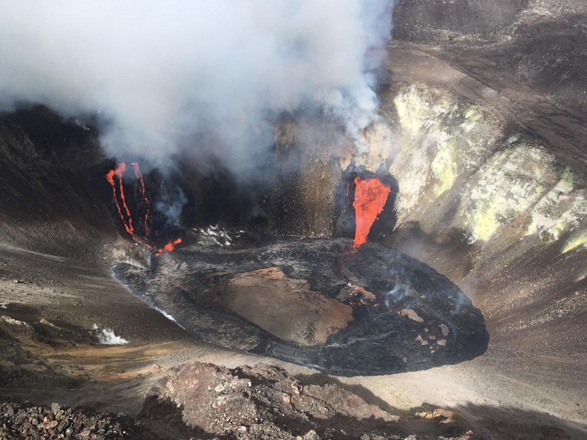 Aerial view of a volcanic crater with three streams of lava and yellow sulfur deposits