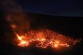 Glowing lava lake in a volcanic crater at night