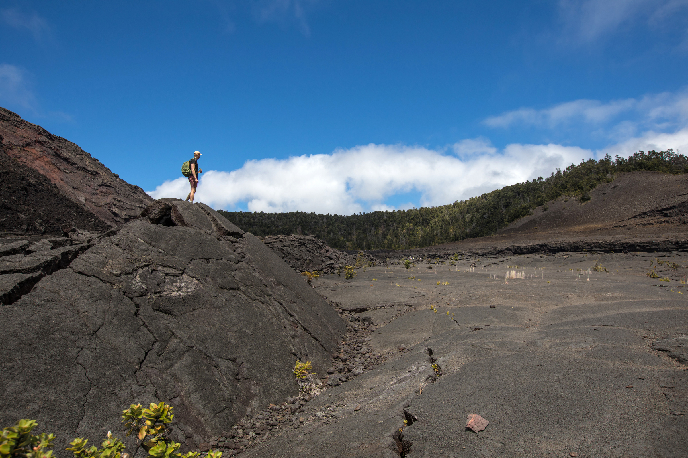 Person practicing social distance on the Kīlauea Iki Trail Person standing on a boulder