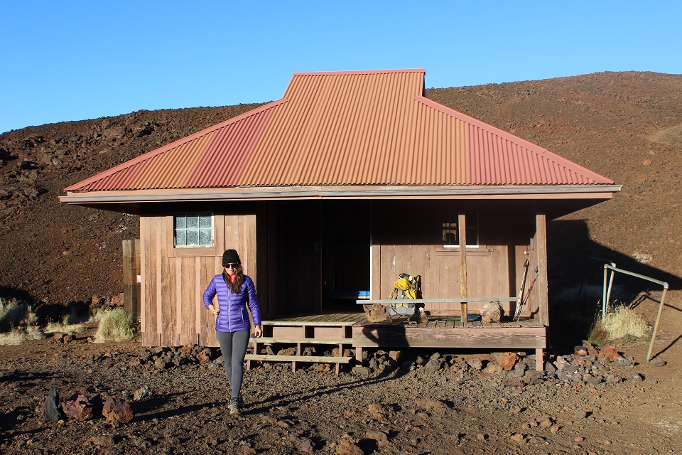 960-20170715_Hiker at Red hill cabin_J.Ferracane A hiker in cold weather garb on the deck of a rustic red cabin