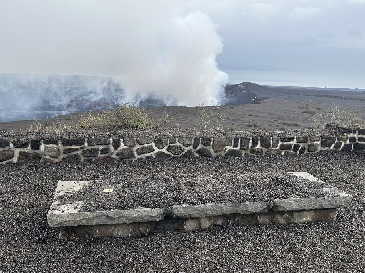 Cinder rock piled up on a viewing platform and stone bench at a volcanic overlook