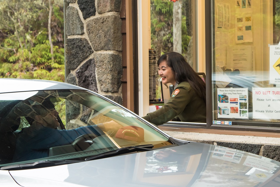 Ranger Shelley accepts a credit card payment from a visitor at the entrance station A park ranger in a booth accepts a credit card from a park visitor inside his vehicle