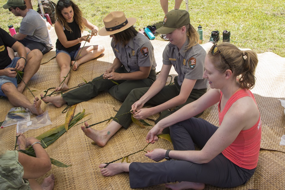Park rangers demonstrate how to make a ti leaf lei