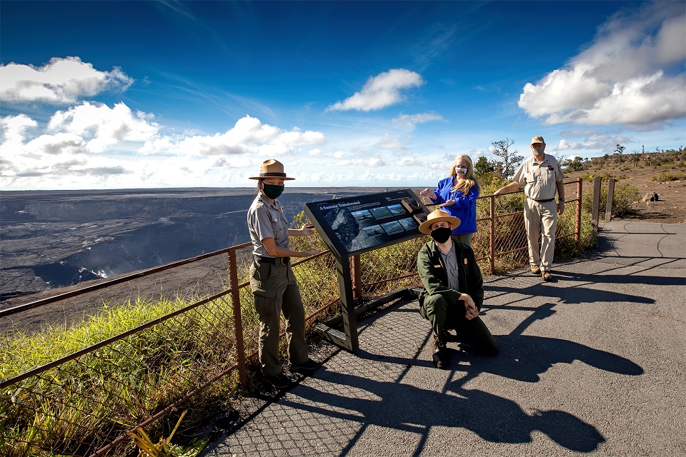 New wayside exhibit sign at Kilauea Overlook Four people pose near a new sign at an overlook