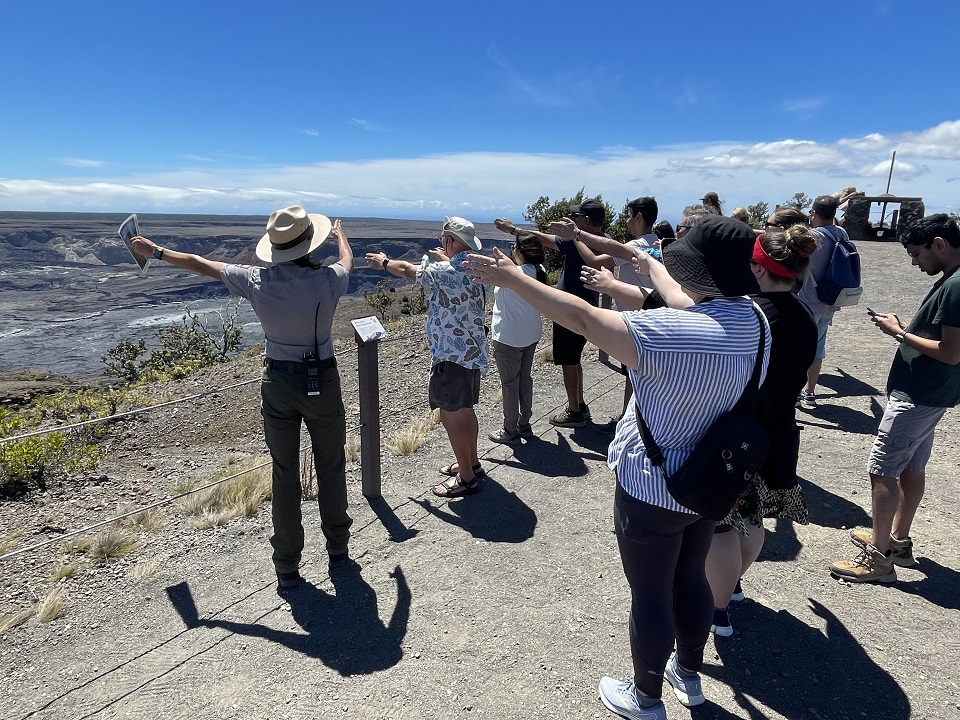 960-HAVO_20240924_Ranger-Mequette-Life-on-the-Edge-program_J.Ferracane A park ranger demonstrates how volcanoes work to a group of visitors on the edge of Kilauea volcano