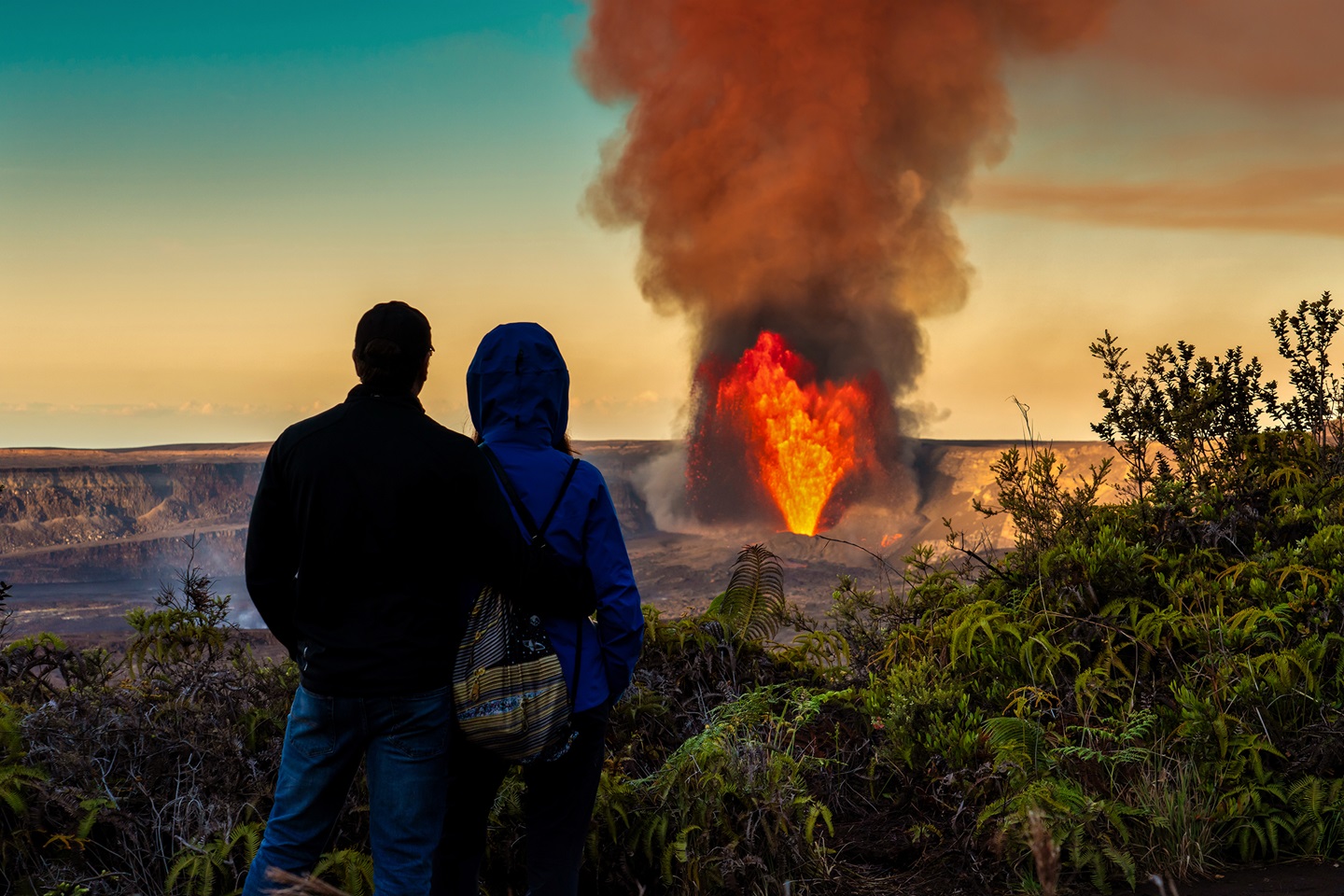 A couple watches lava erupt and fountain from a crater at the summit of Kilauea volcano