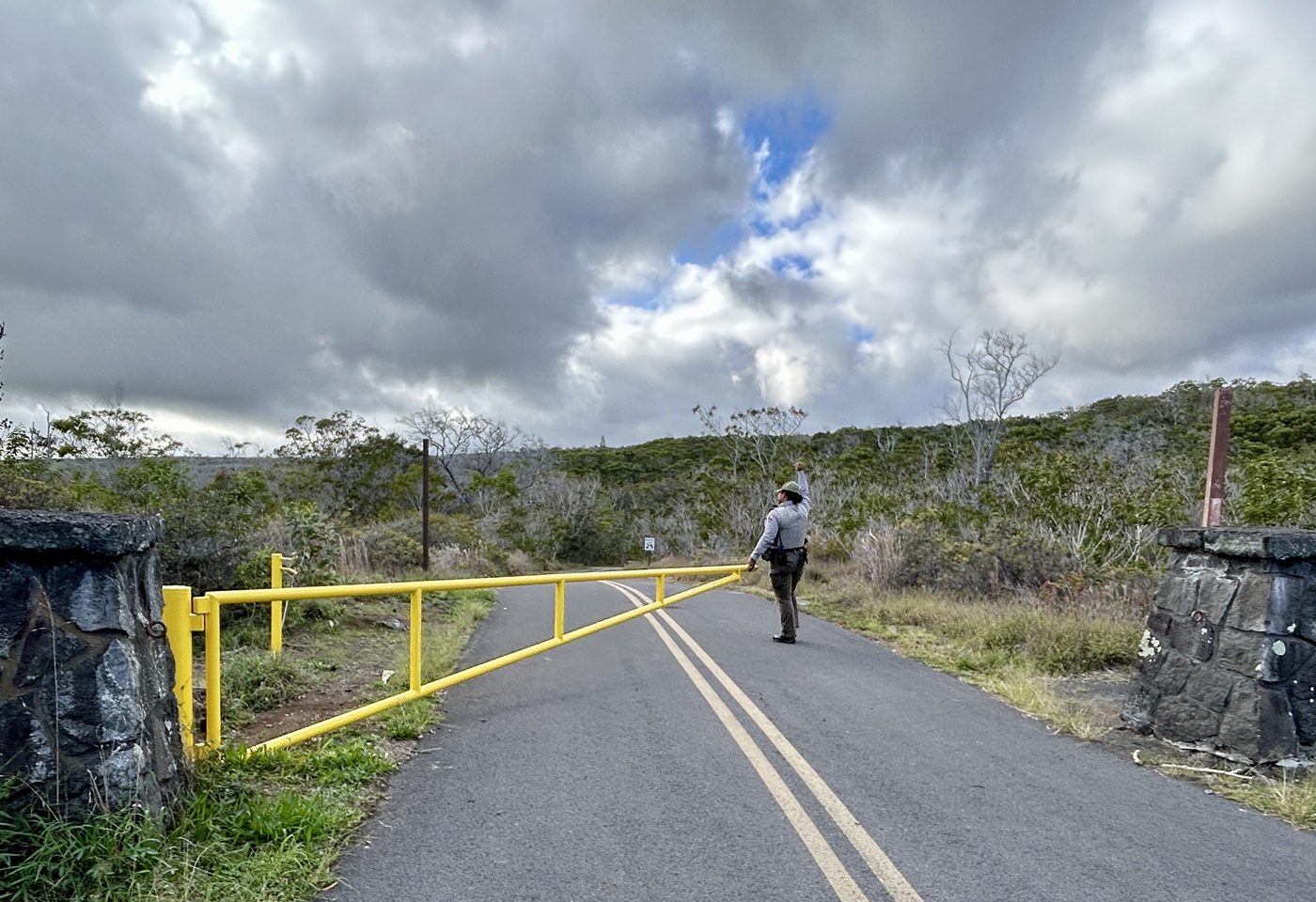 A park ranger opens a yellow gate to open a road